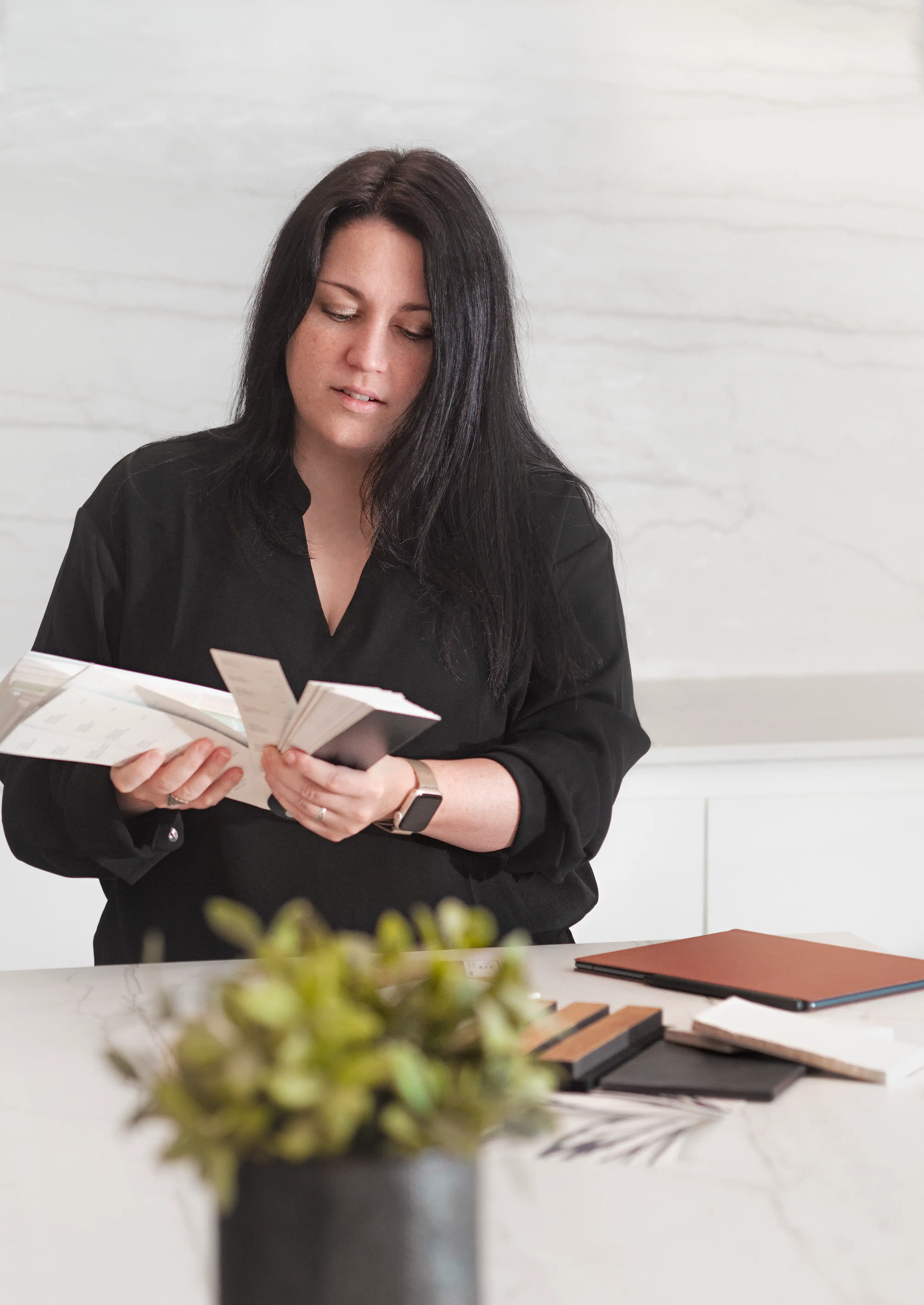 Sarah Brown, designer d'intérieur, examinant des échantillons de couleur dans une cuisine moderne en marbre