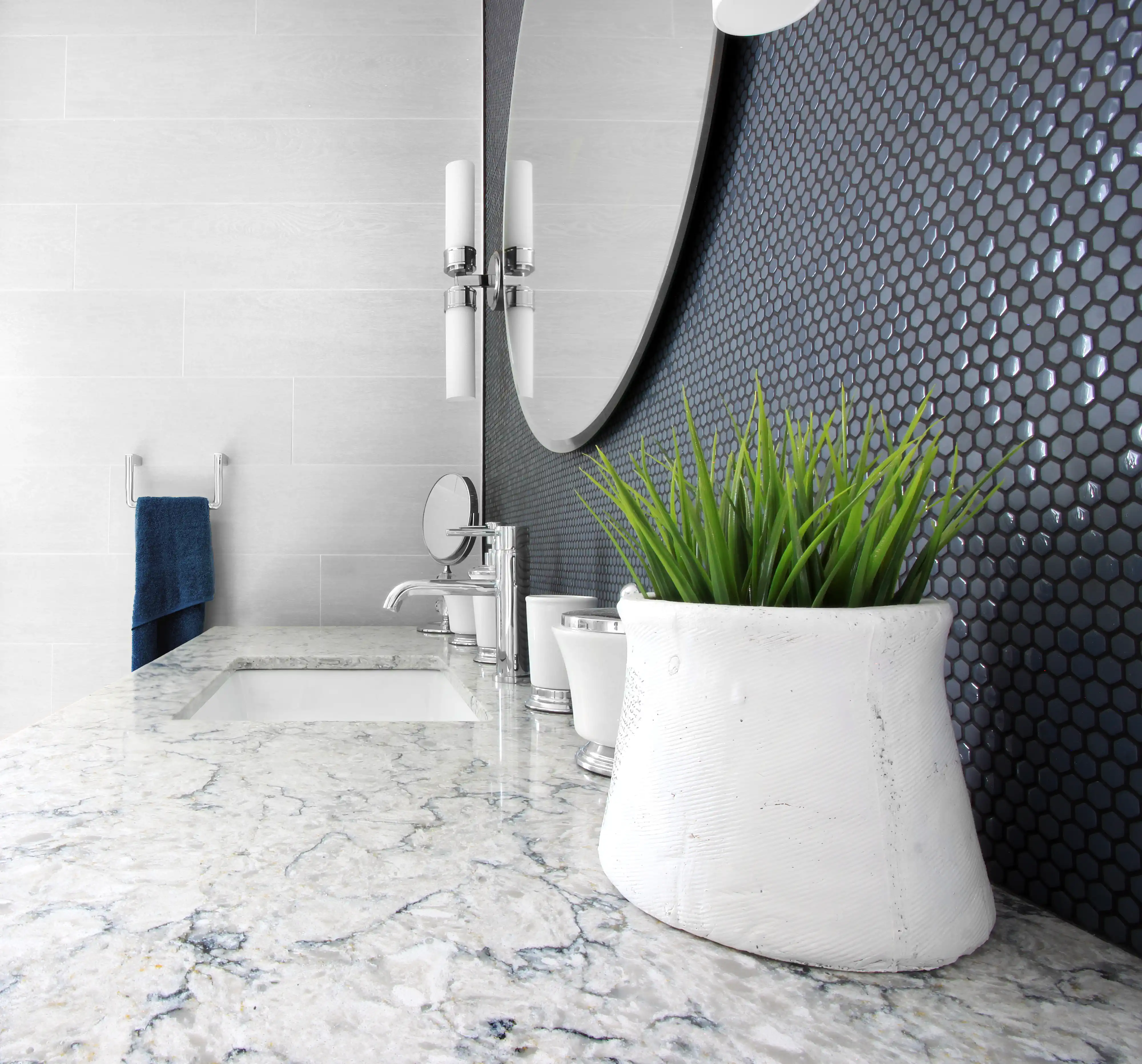 A modern bathroom sink and countertop with white marble and dark blue hexagonal tiles, interior by Sarah Brown Design