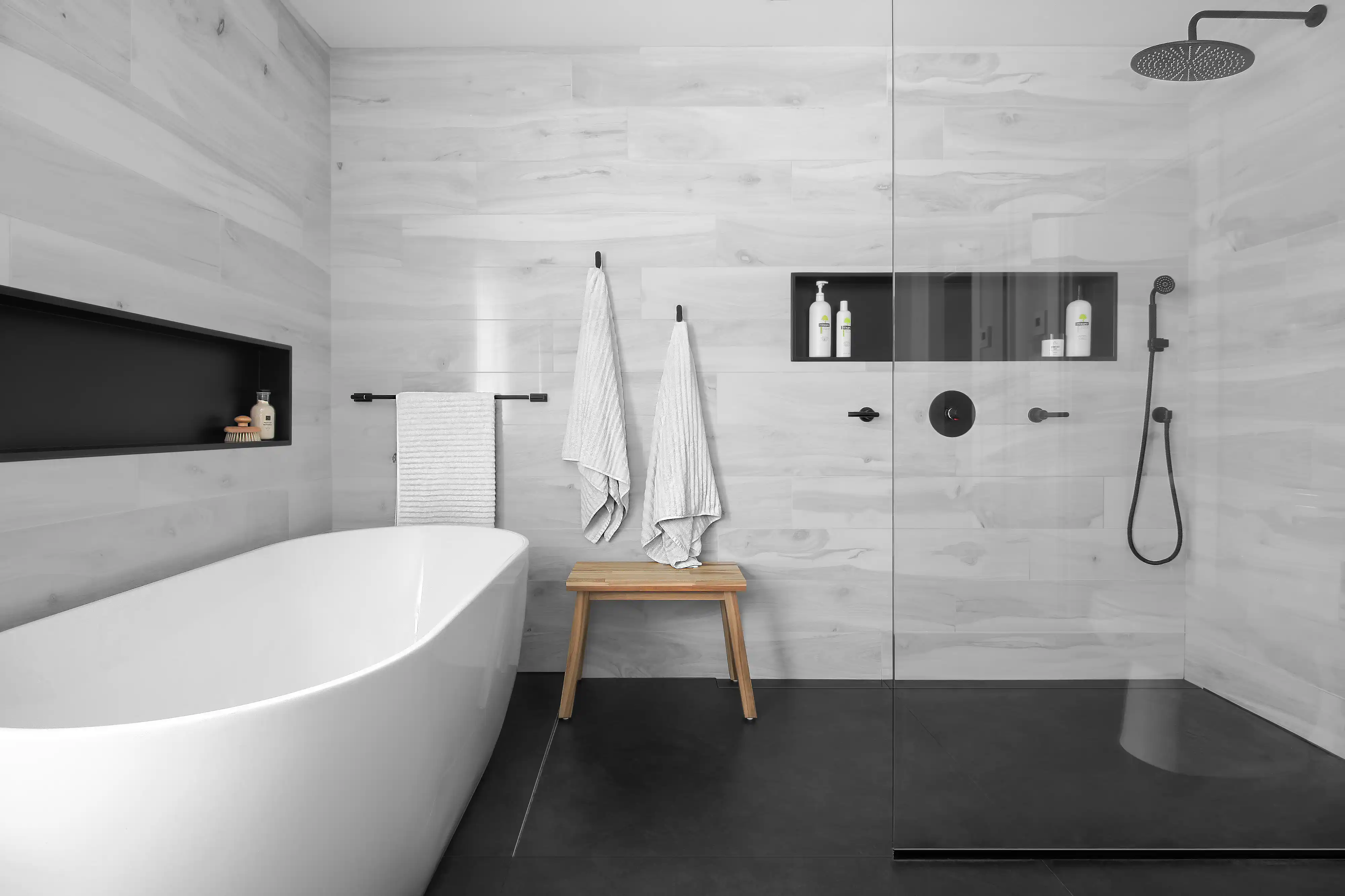 Salle de bain moderne avec un thème noir et blanc, comprenant une baignoire autoportante blanche et une douche à l'italienne, intérieur signé Sarah Brown Design