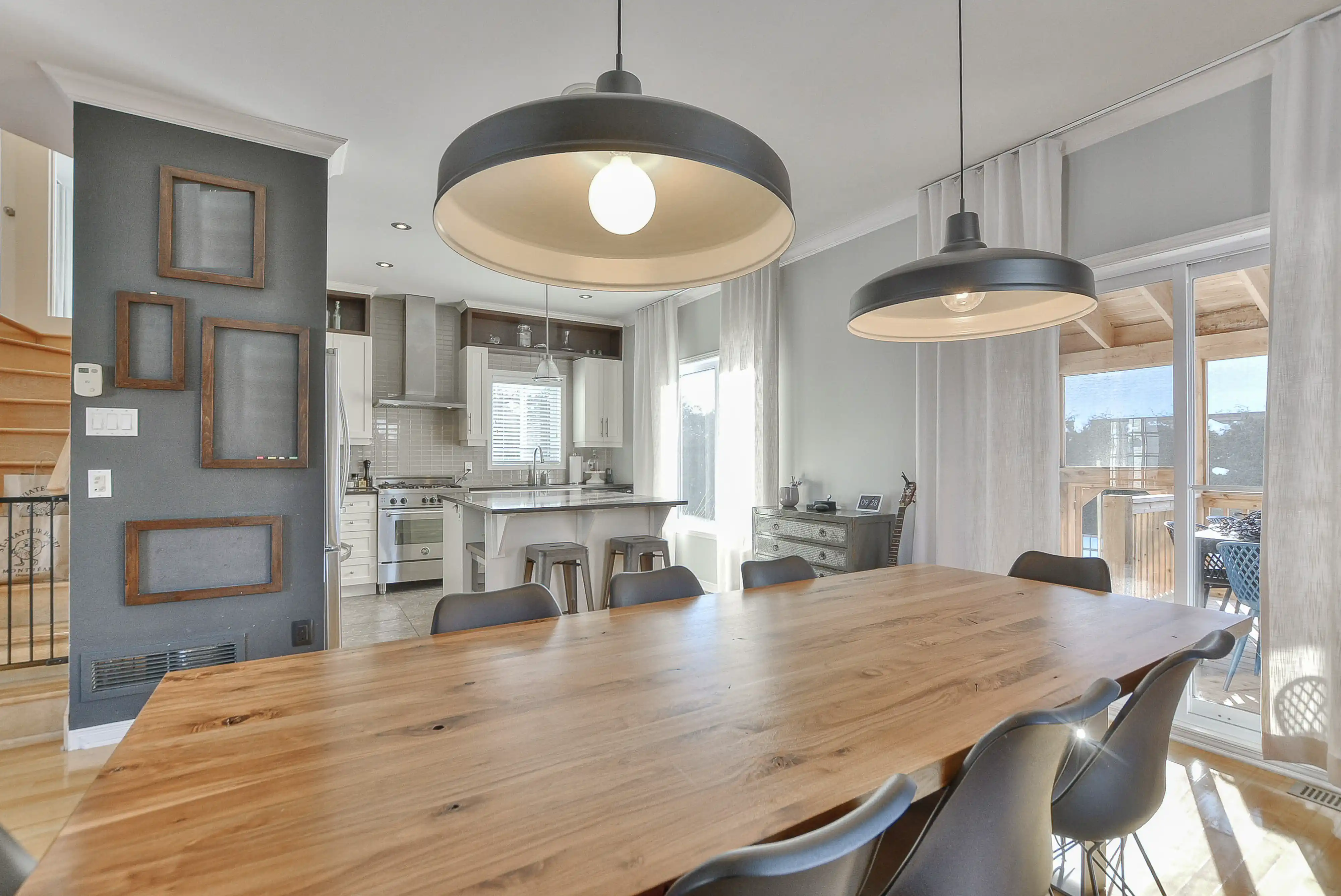 Salle à manger moderne avec une grande table en bois, des chaises noires et une vue sur la cuisine, intérieur signé Sarah Brown Design
