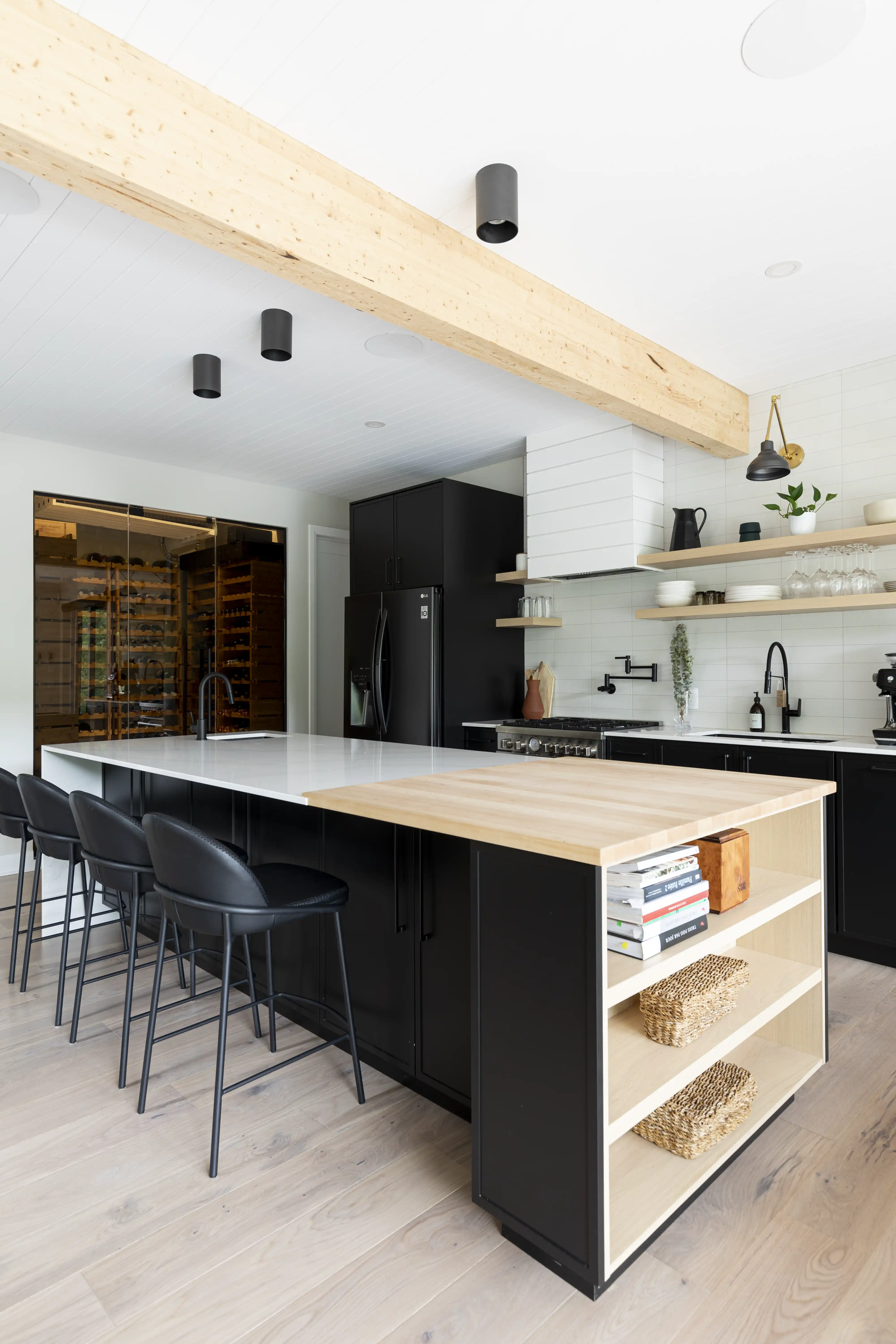 A modern kitchen with a wooden island and black appliances, interior by Sarah Brown Design