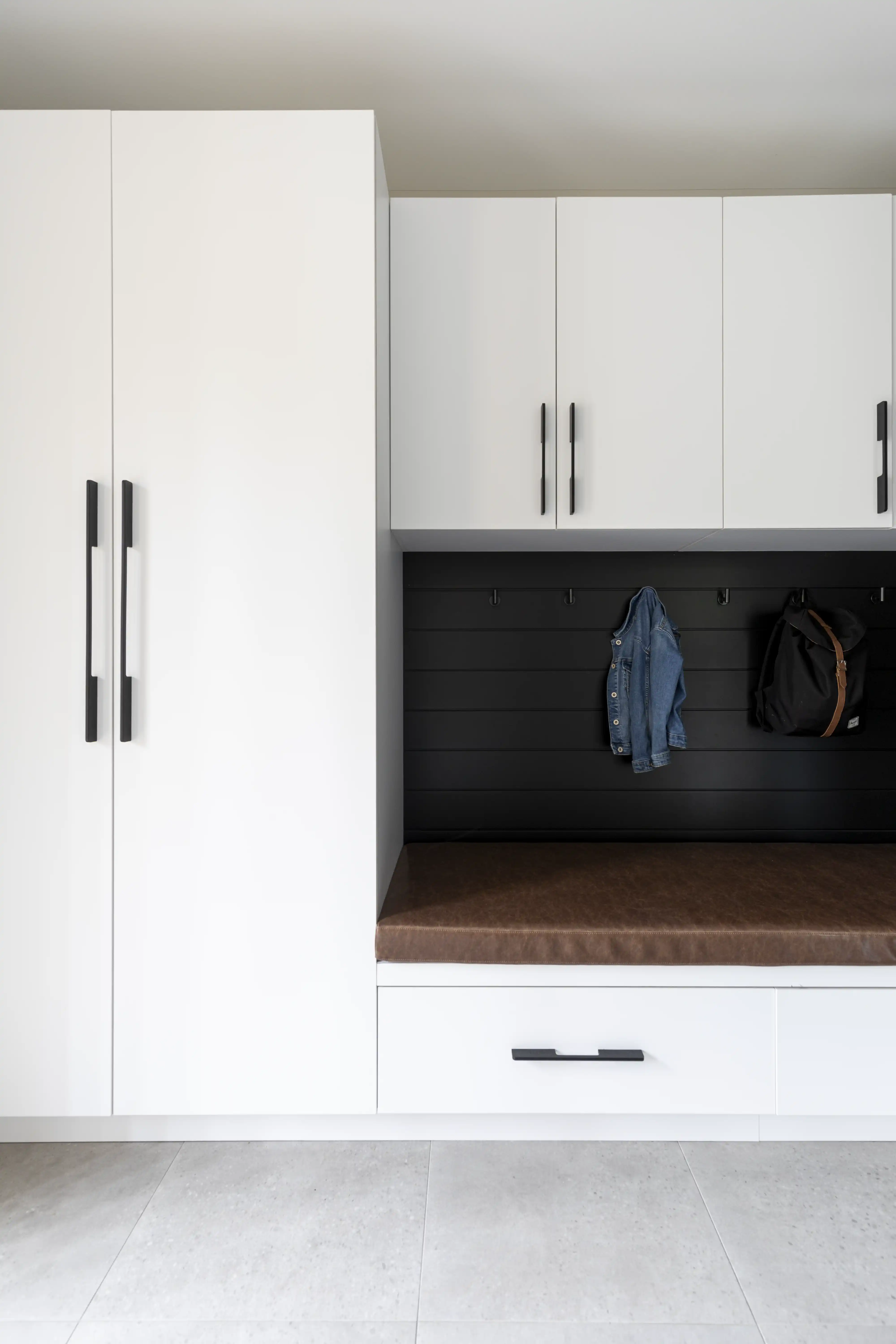 A modern, minimalist entryway with a built-in closet and bench, interior by Sarah Brown Design