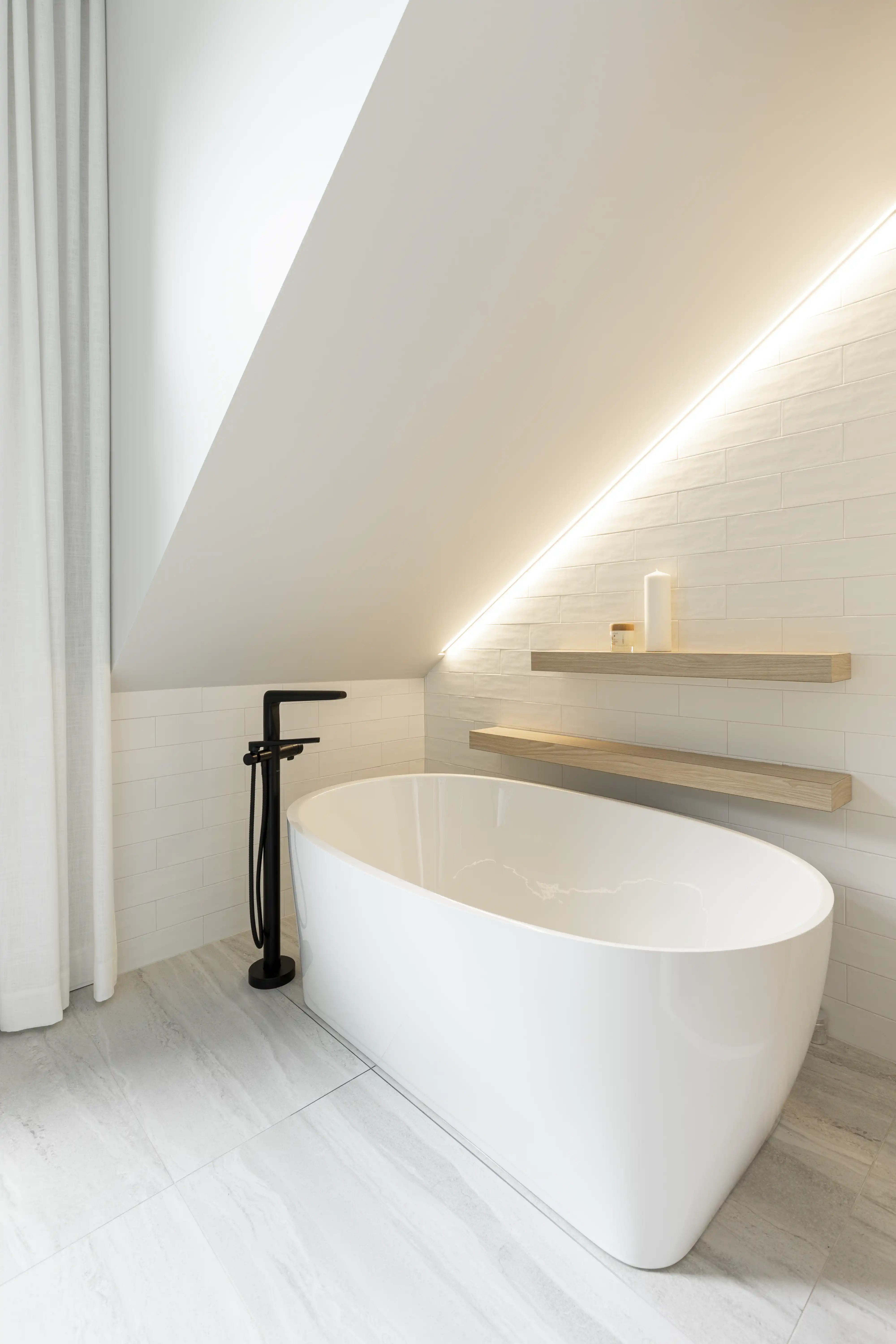 A white marble bathroom with a freestanding bathtub and a window, interior by Sarah Brown Design