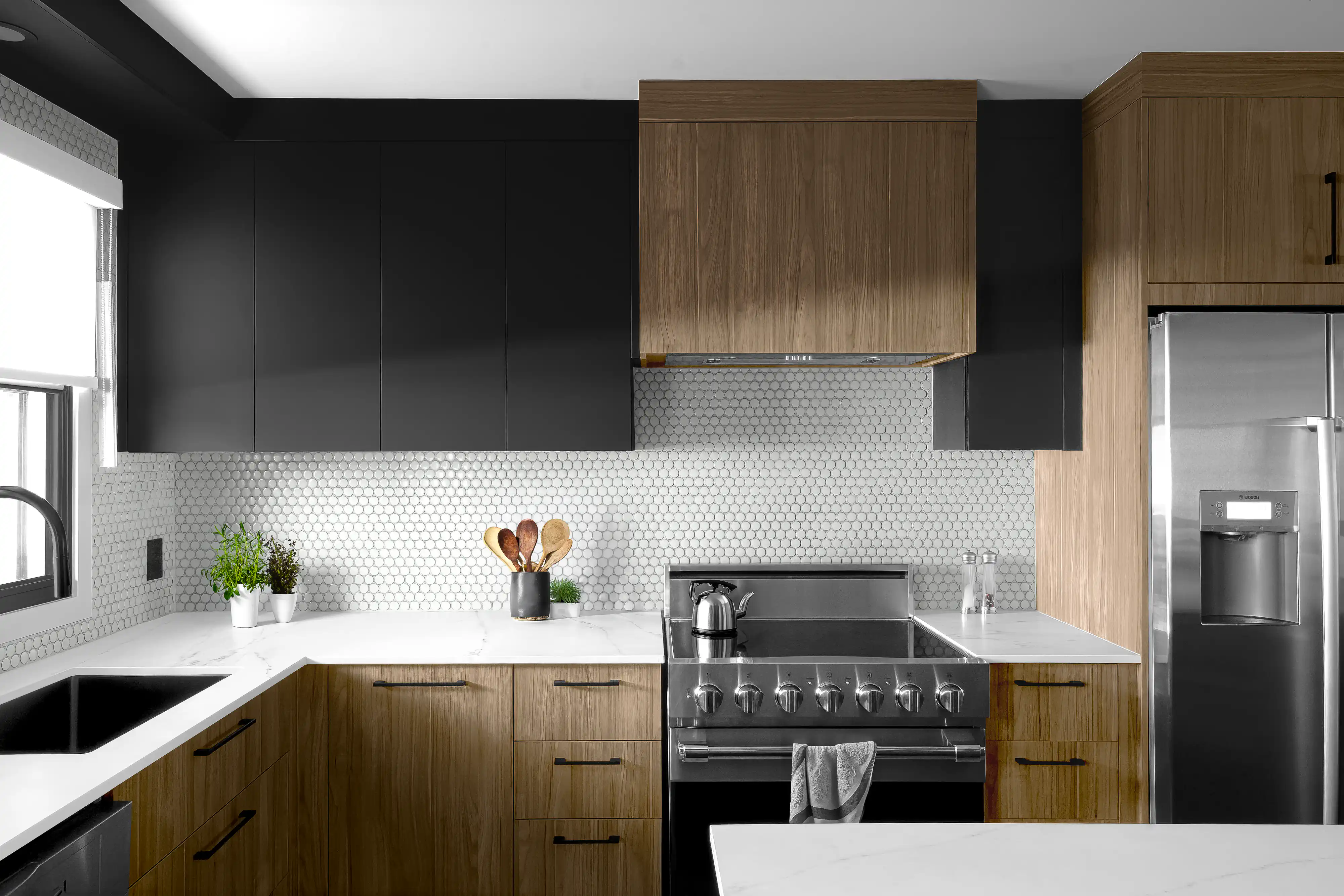 Modern kitchen with black cabinets, wooden accents, and round mosaic backsplash tiles, interior by Sarah Brown Design